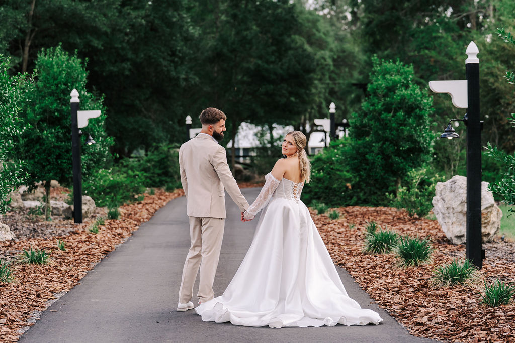 Bride and groom holding hands and walking down a garden path after their wedding ceremony.