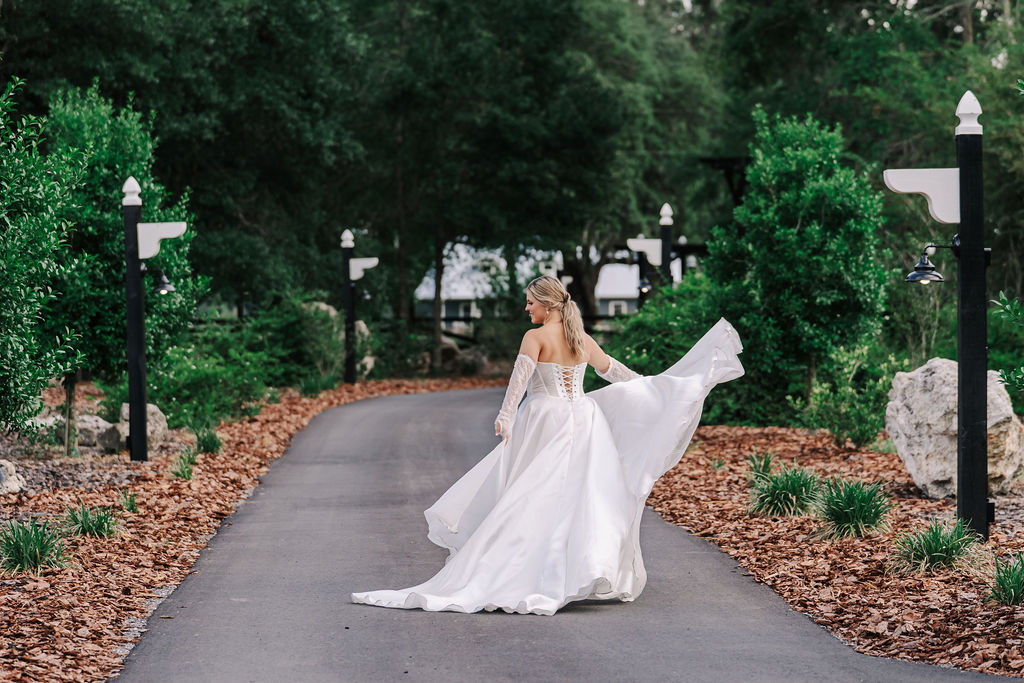 Bride twirling in wedding dress on outdoor garden pathway